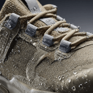Close-up de um calçado multifuncional que une performance e design: cabedal em tecido CORDURA® homologado pela ITM para alta resistência à abrasão, zonas de flexão respiráveis e painéis selados com tecnologia DRYSHIELD® que repelem a água e garantem impermeabilidade. A silhueta mistura outdoor e urbano, com solado de alta tração, costuras reforçadas e acabamentos minimalistas — pensado para a cidade, trilhas leves e dias chuvosos.
